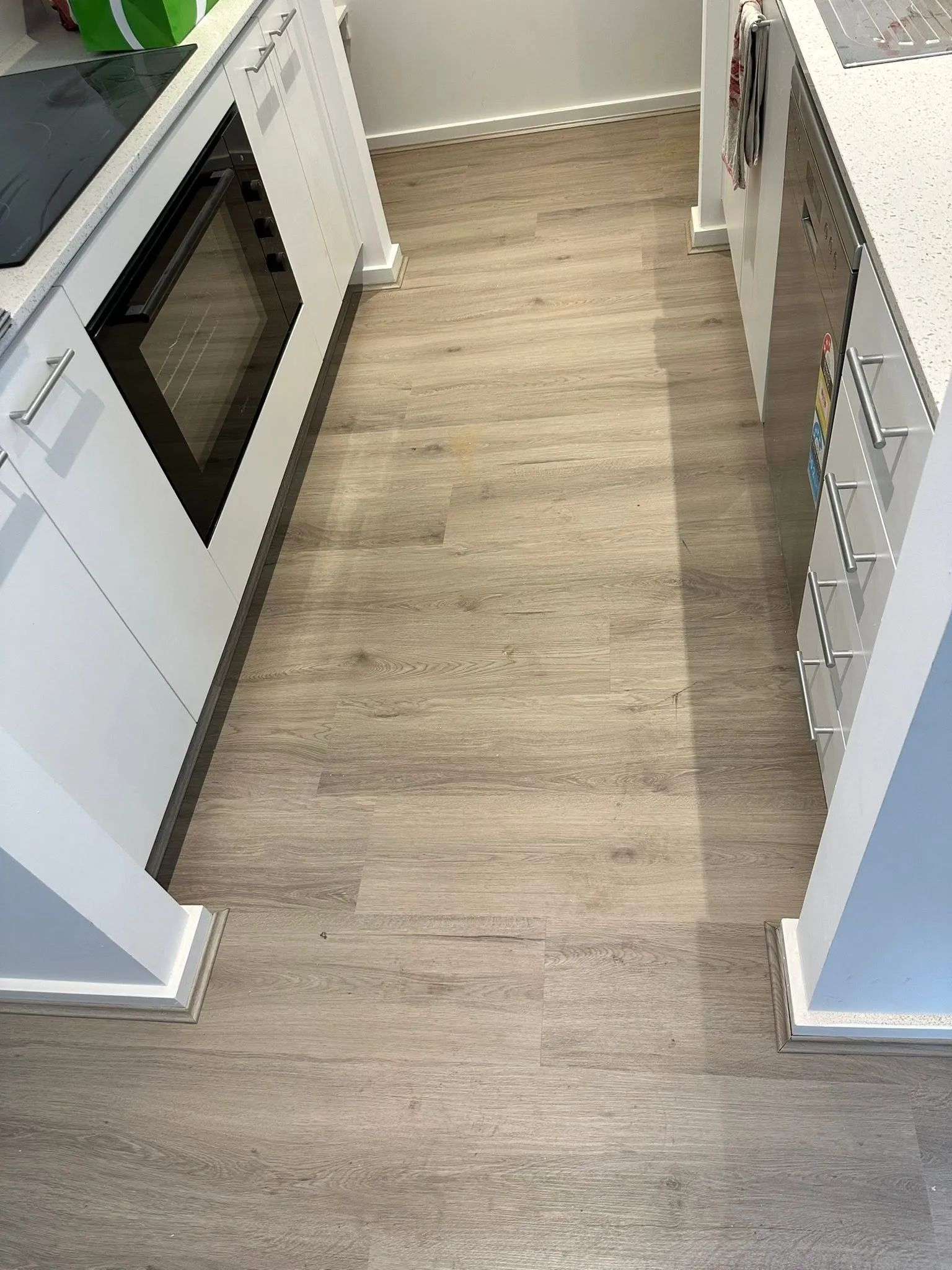 Tan Oak hybrid flooring between white kitchen cabinets