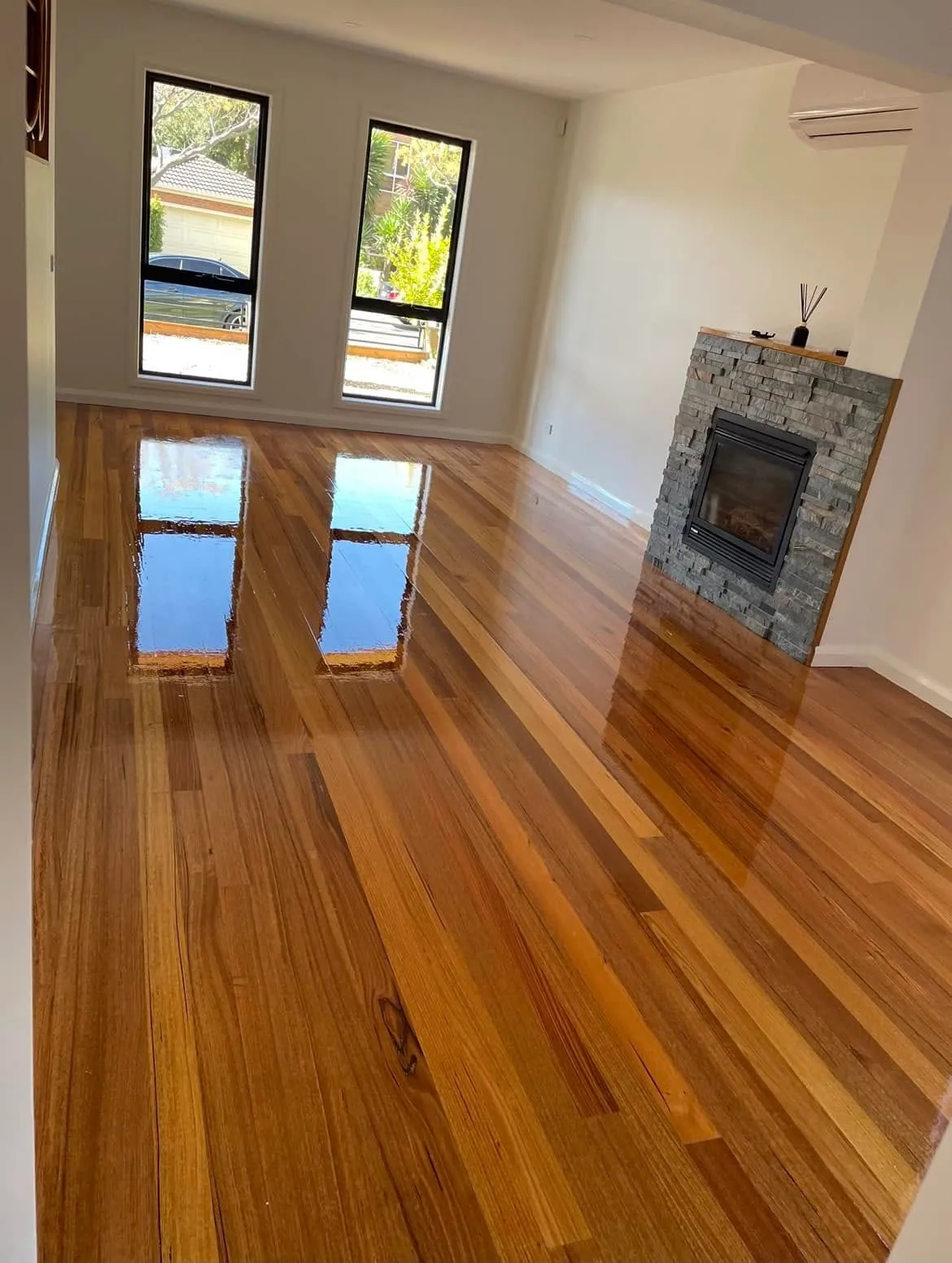 High-gloss timber flooring in a living room with a stone fireplace