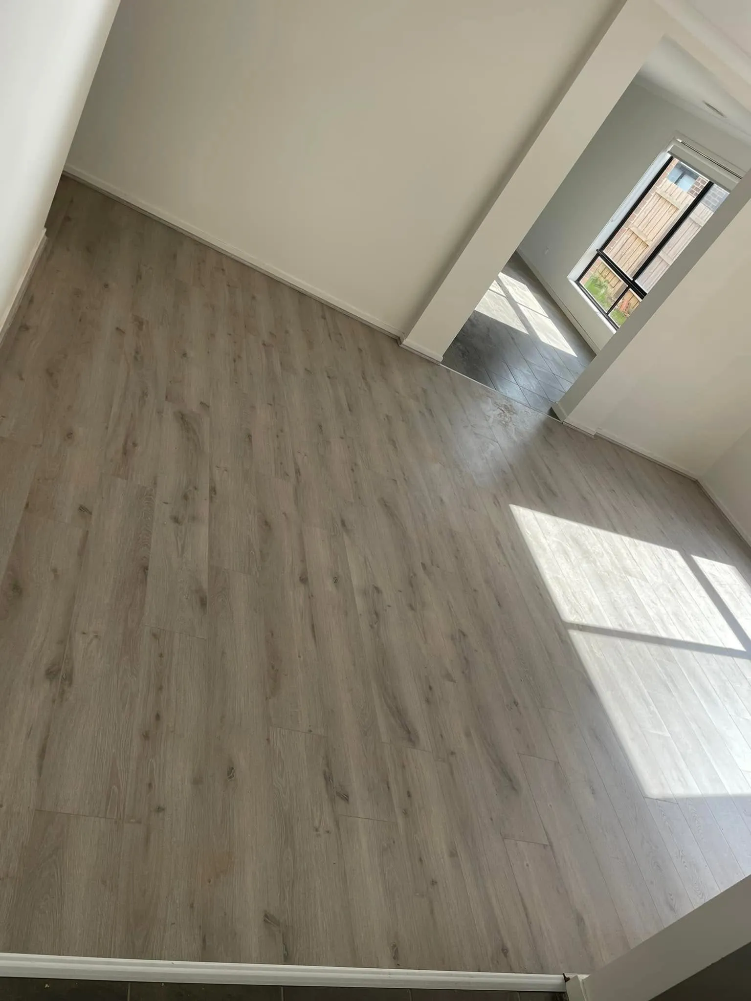 Light grey flooring in a room with a window looking onto a garden