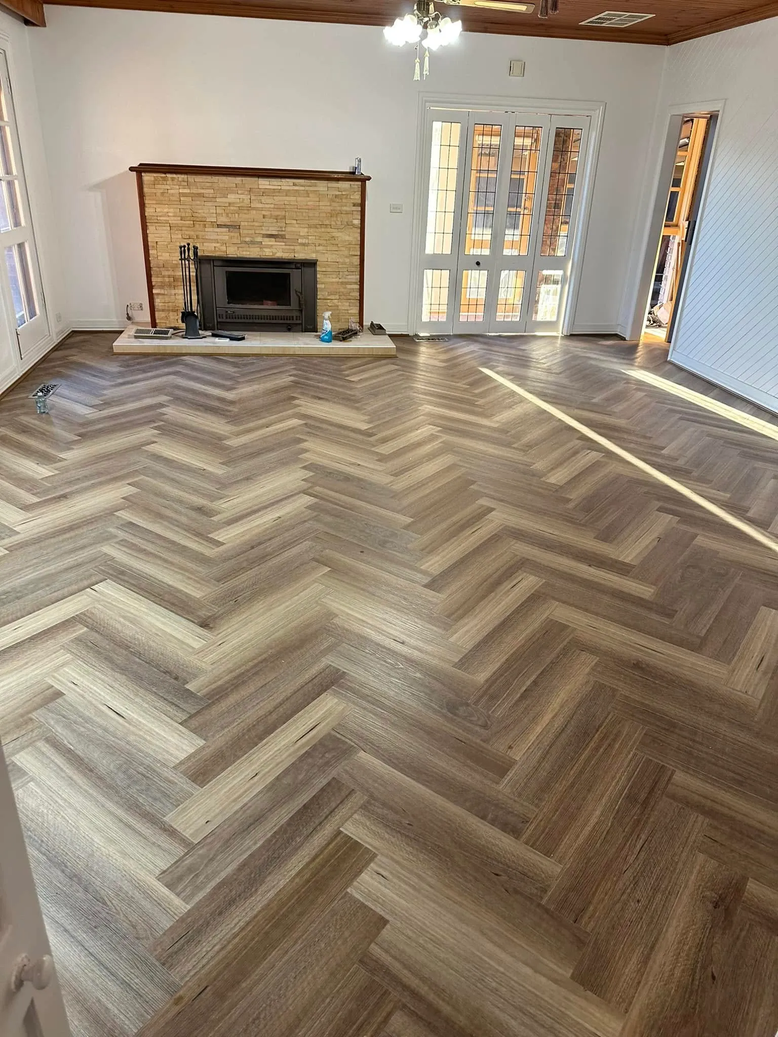 Grey-brown herringbone flooring in a living room with a stone fireplace