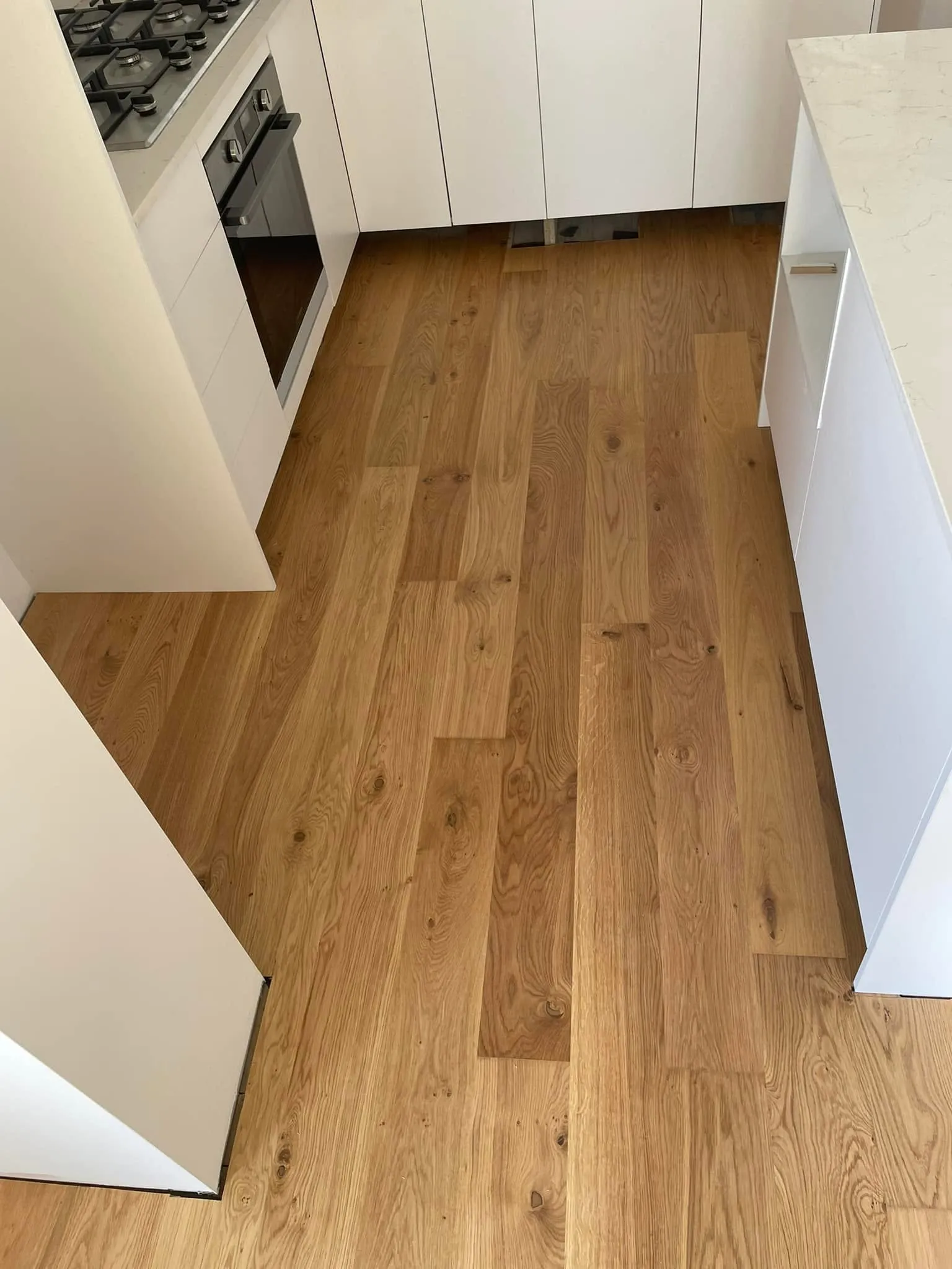 Honey-toned oak flooring in a kitchen with white cabinetry