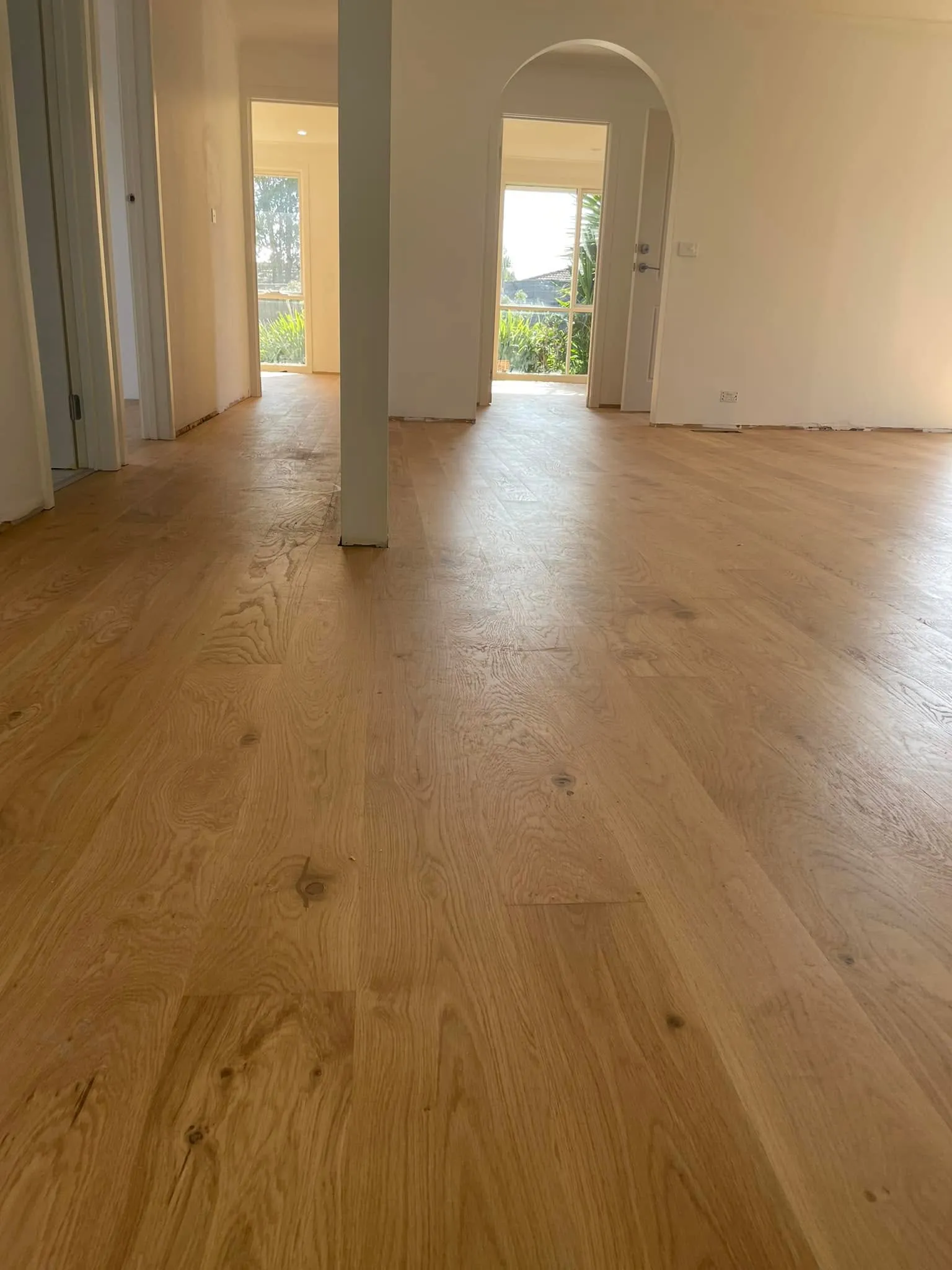 Honey-toned oak flooring in an open living space with two garden doorways